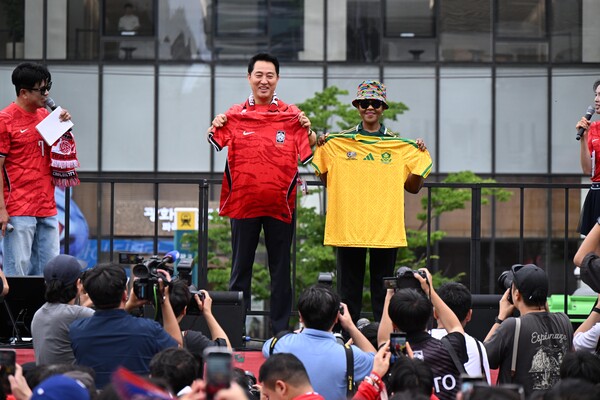 25일 오세훈 서울시장이 광화문광장 일대에서 열린 '2026 북중미 월드컵 대한민국-남아프리카공화국 공동응원전'에서 신디스와 음쿠쿠 주한남아공대사와 유니폼을 교환하고 있다.(사진_서울시)