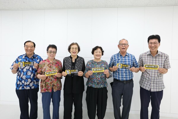 어르신들이 안전한 도로 환경 조성을 돕는 '어르신이 타고 있어요', '배려 감사합니다' 차량용 자석 스티커를 들고 환하게 미소 짓고 있다.(사진_신천지 부산야고보지파)